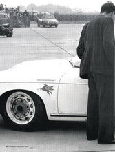 Load image into Gallery viewer, Black-and-white photo of a classic white sports car displaying a Pegasus decal near the front wheel
